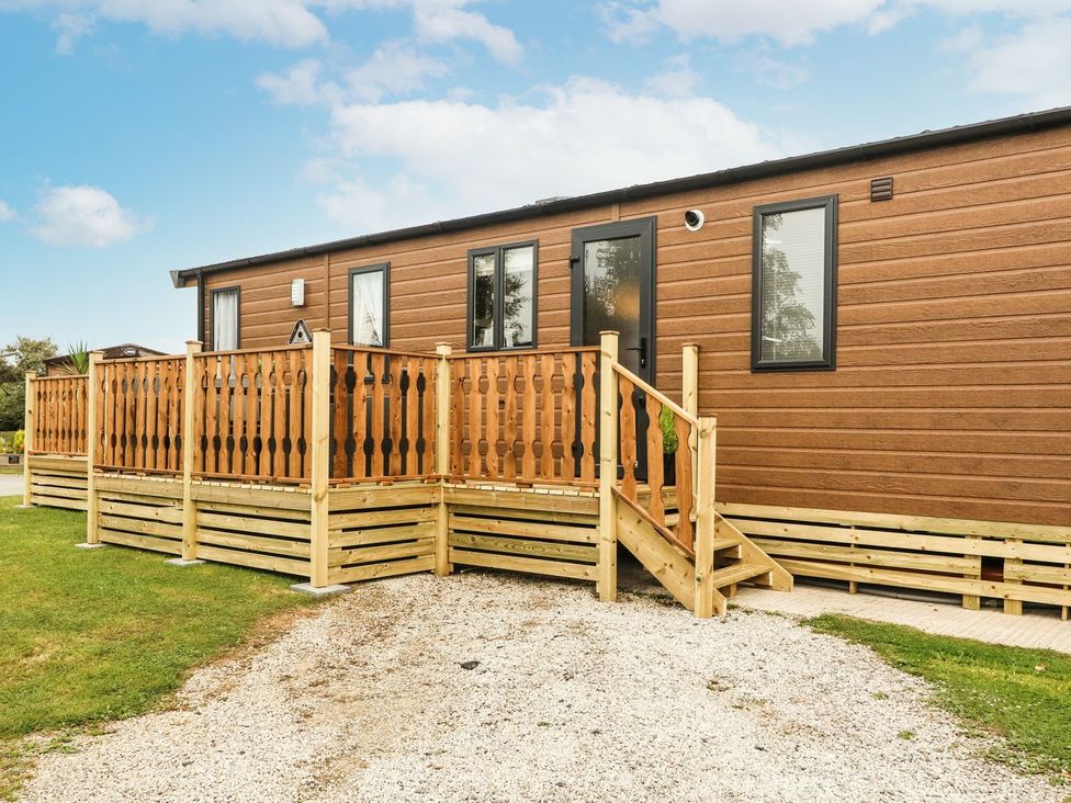 A mobile home with a wooden deck and stairs at Hedgehog Lodge Carnforth