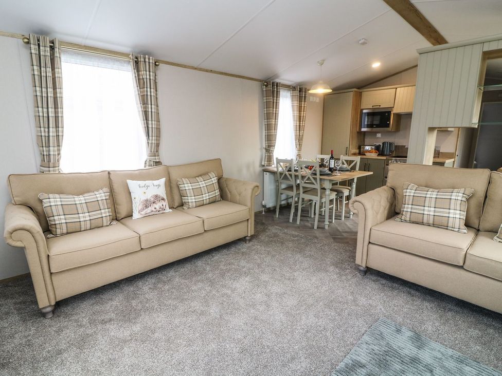 A living room with two sofas and a dining table at Hedgehog Lodge Carnforth
