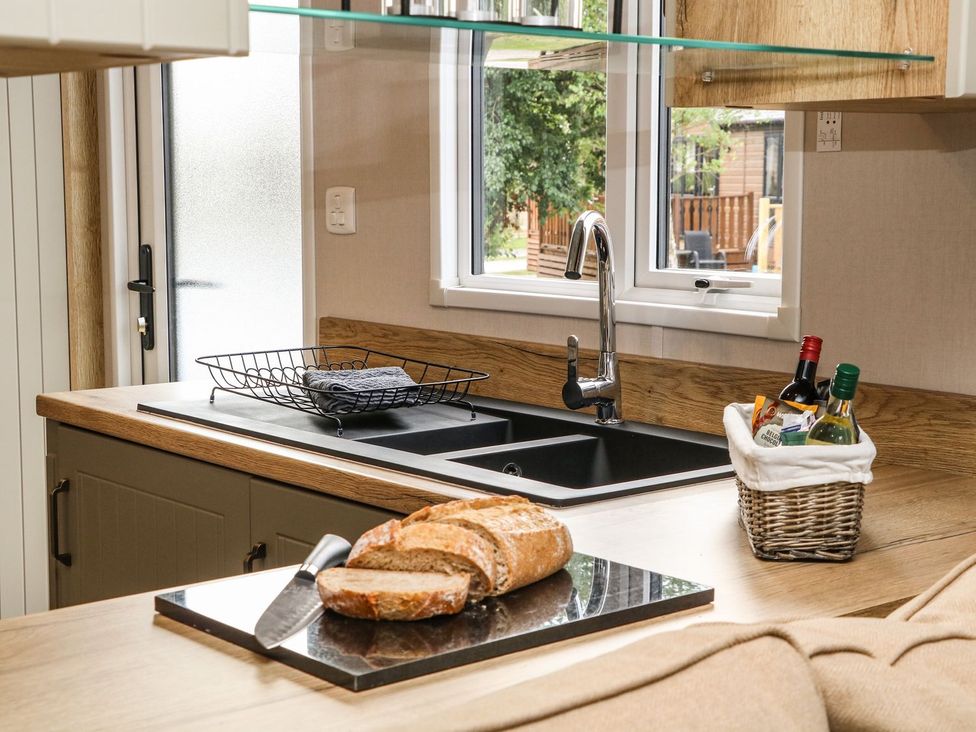 A kitchen with a sink and bread on a cutting board at Hedgehog Lodge in Carnforth