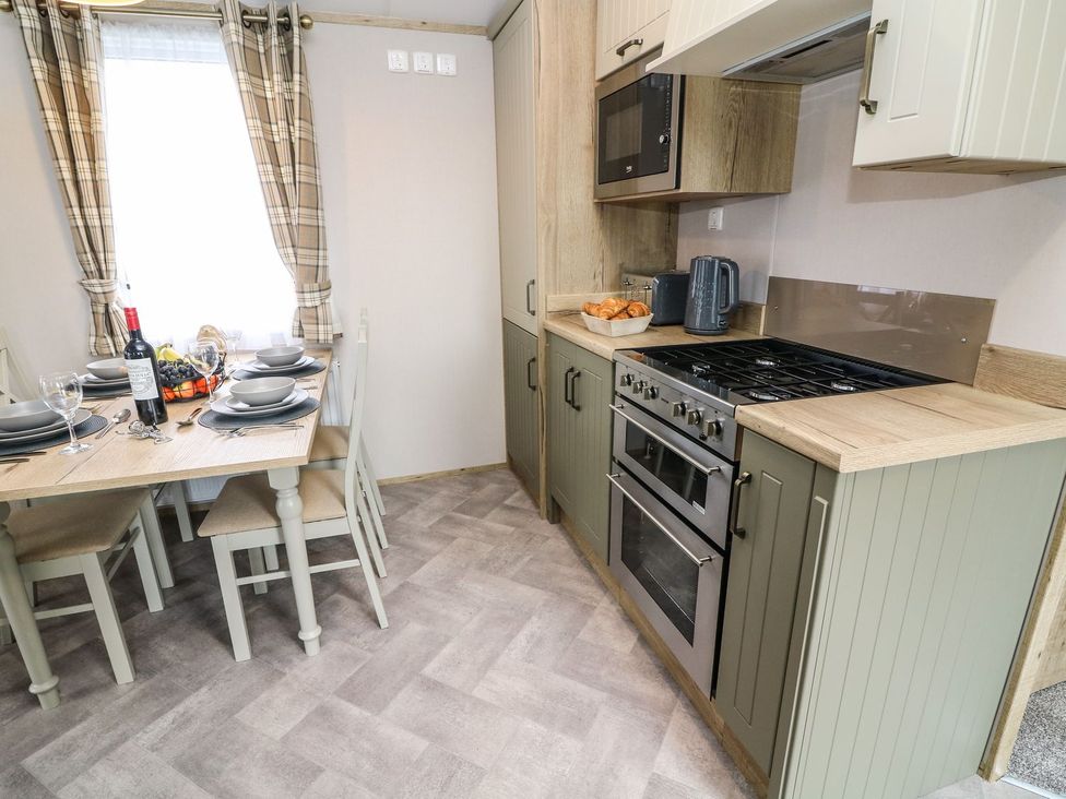 A kitchen with a dining table and chairs at Hedgehog Lodge in Carnforth