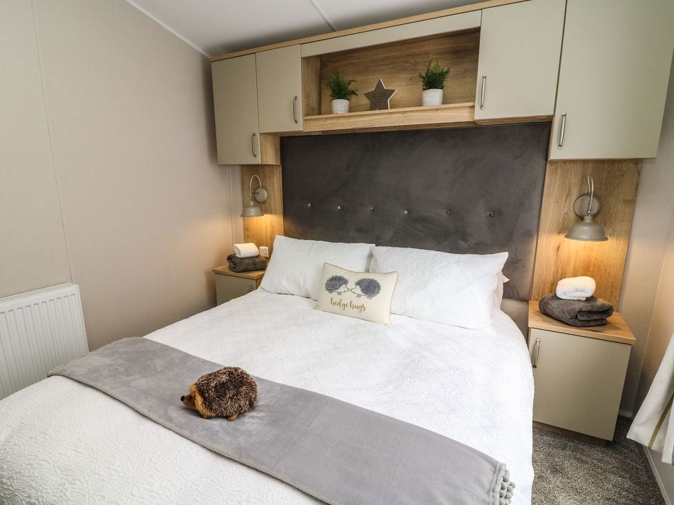 A bedroom with a bed and bedside lamp at Hedgehog Lodge in Carnforth