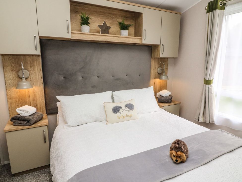 A bedroom with a bed, bedside tables, and lamps at Hedgehog Lodge in Carnforth