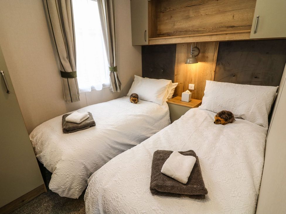 A bedroom with two single beds and a bedside lamp at Hedgehog Lodge in Carnforth