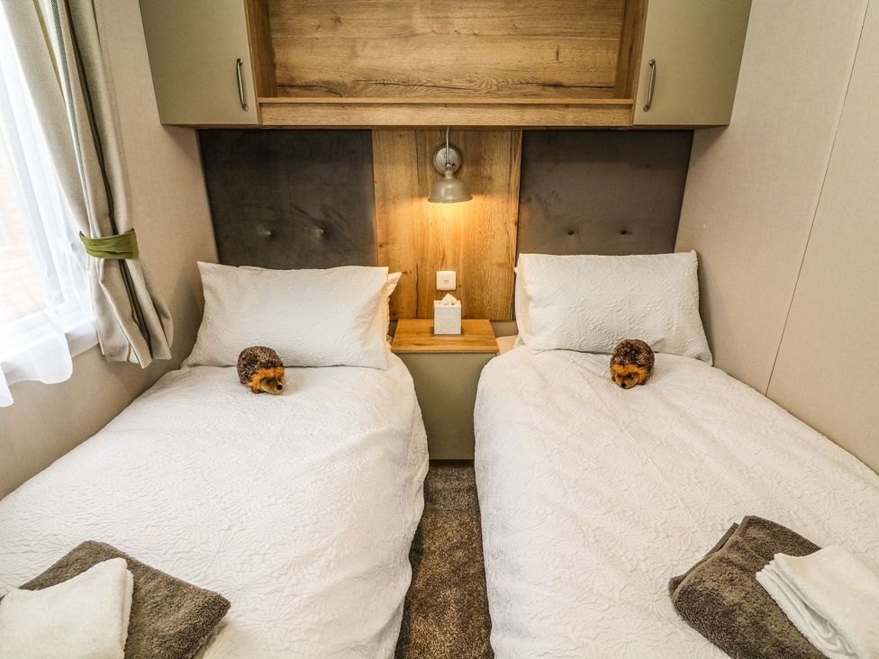 A bedroom with two beds and a bedside table at Hedgehog Lodge in Carnforth