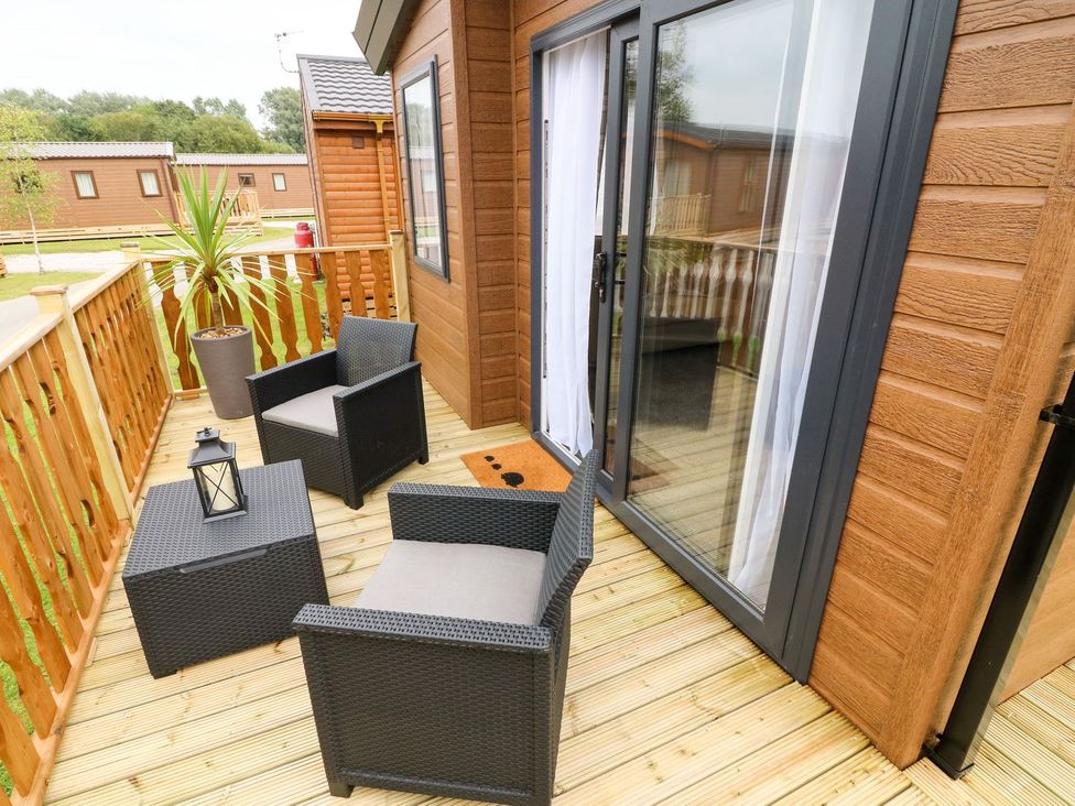 A deck area with chairs and a table at Hedgehog Lodge in Carnforth