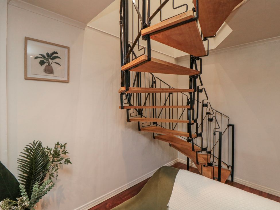 A staircase with wood spiral steps and a plant at 3 Beck Mews Scarborough