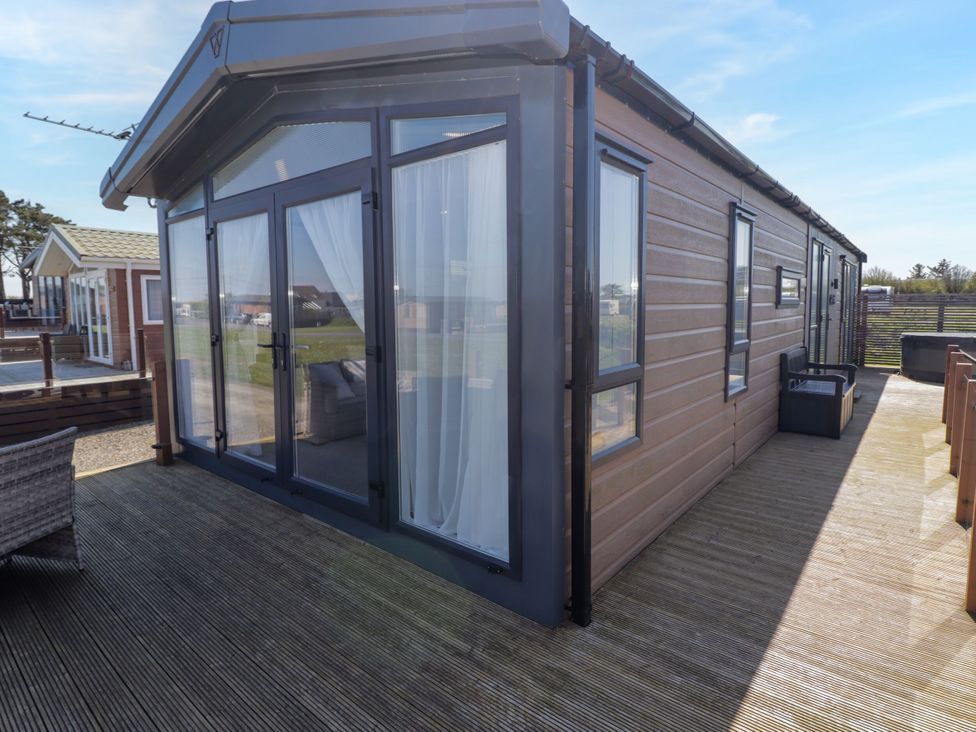An outdoor area with decking and glass doors at Stone Crab Lodge in Haverfordwest