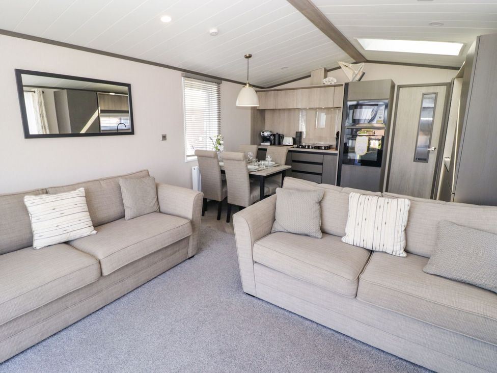 A living room with sofas and a dining area at Stone Crab Lodge Haverfordwest