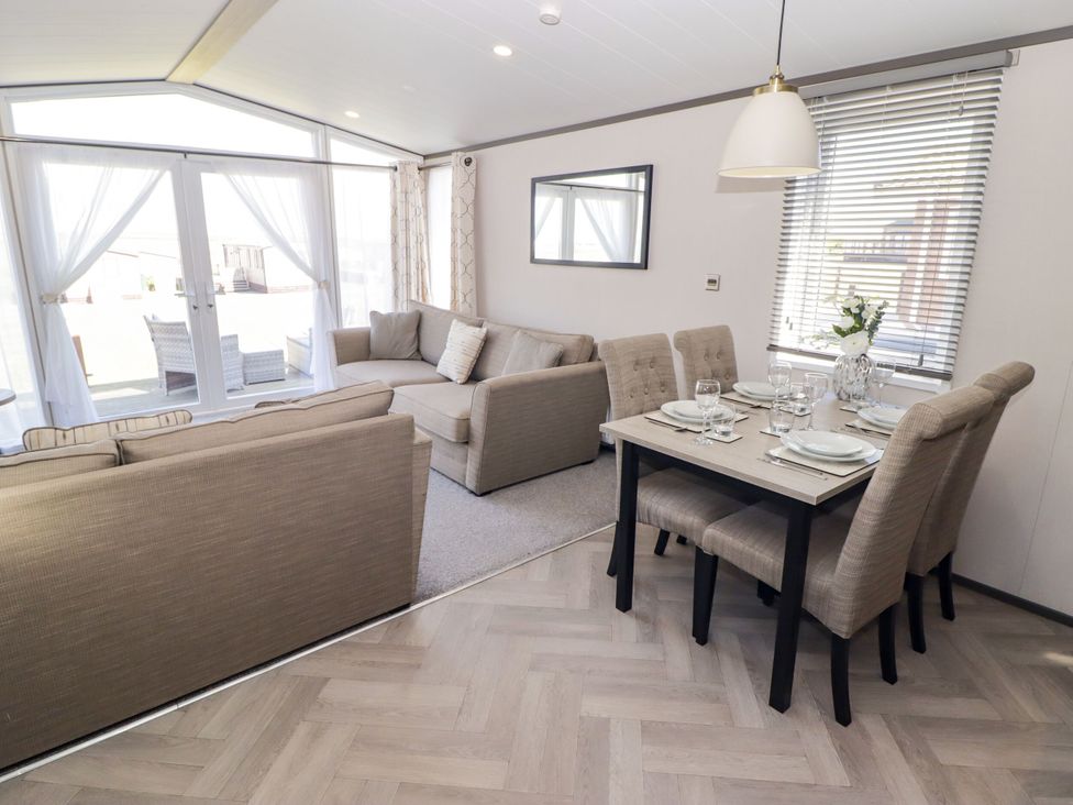 A living room with a sofa and dining area at Stone Crab Lodge in Haverfordwest