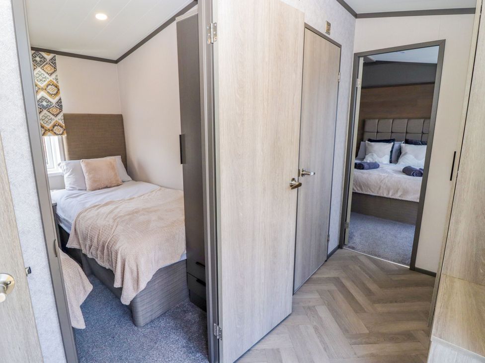 A bedroom with two beds and doors at Stone Crab Lodge in Haverfordwest