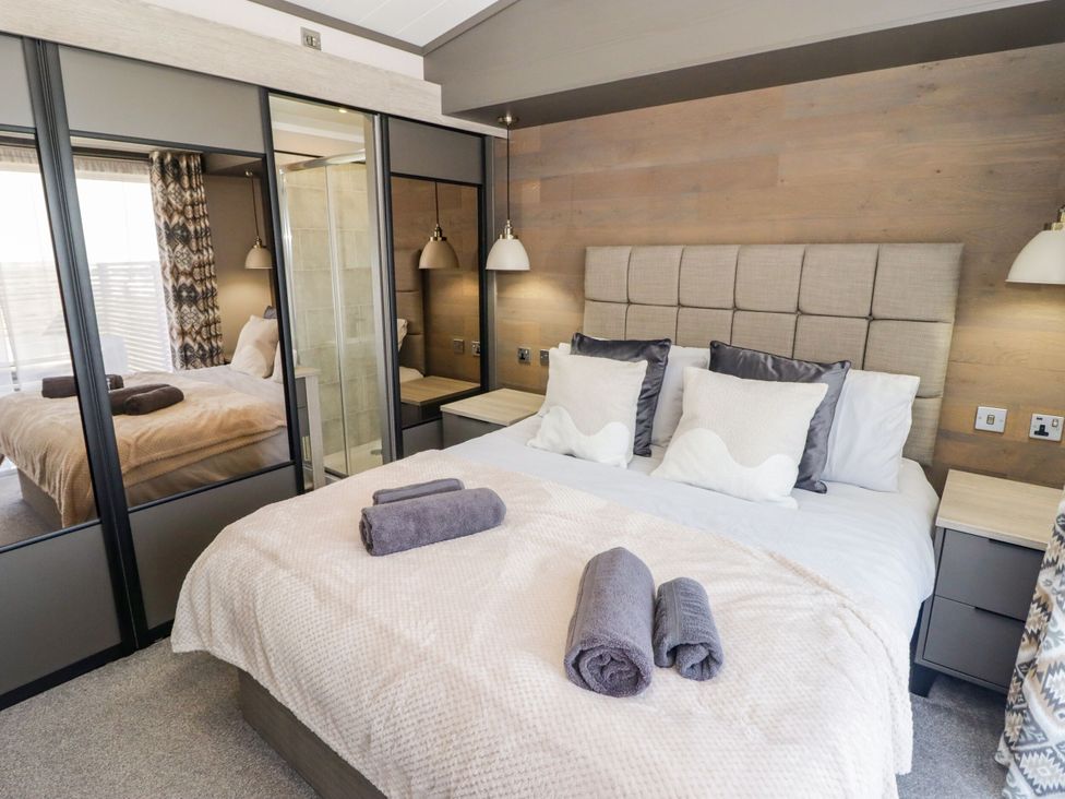 A bedroom with a bed and bedside table at Stone Crab Lodge in Haverfordwest