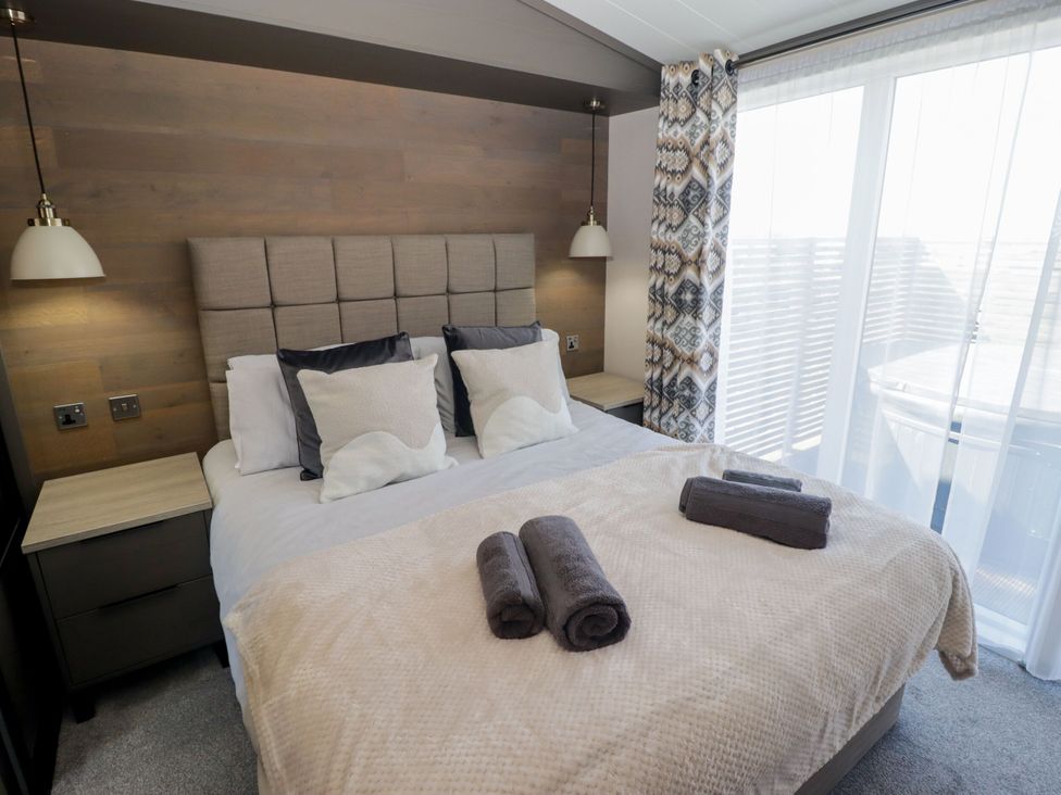 A bedroom with a bed and bedside table at Stone Crab Lodge in Haverfordwest