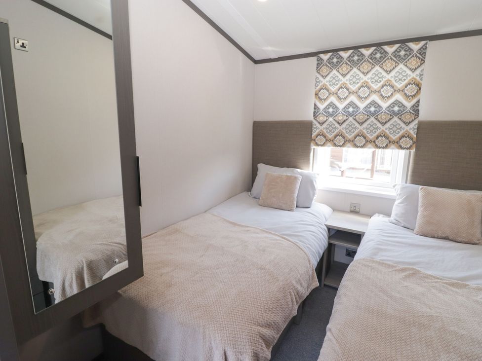 A bedroom with twin beds and a window at Stone Crab Lodge in Haverfordwest