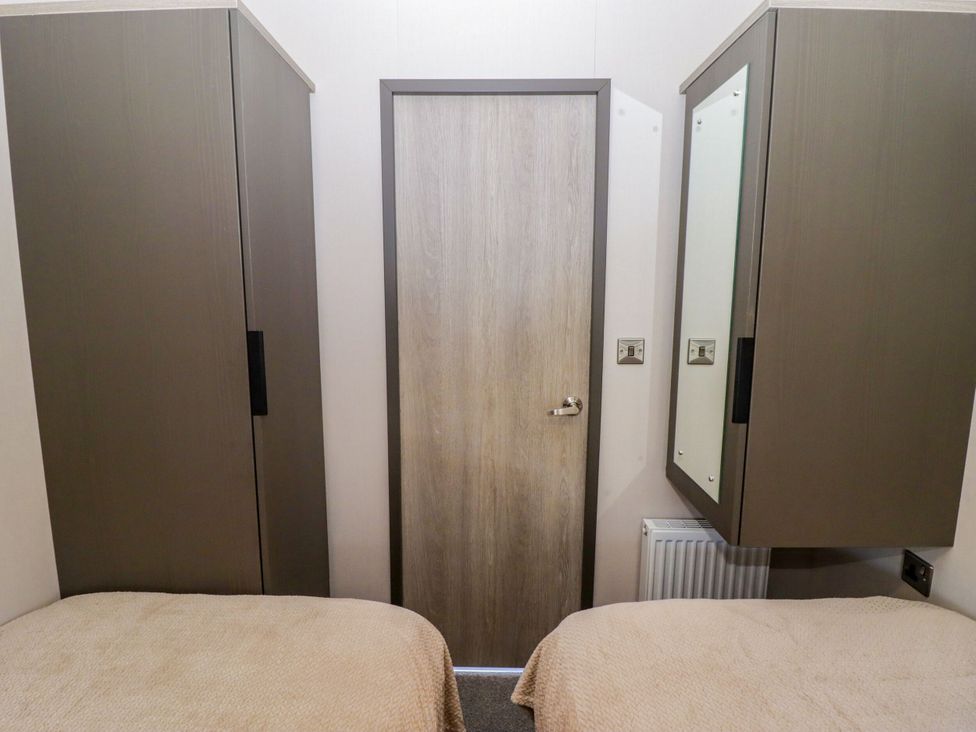 A bedroom with wardrobes and a door at Stone Crab Lodge in Haverfordwest