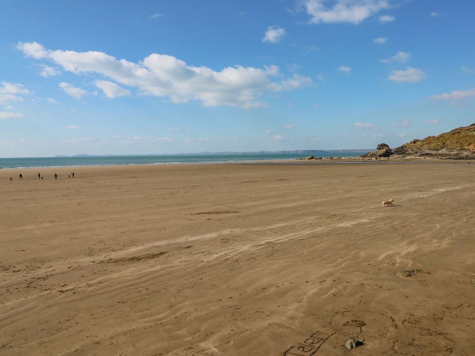 A beach with people walking and a dog at Stone Crab Lodge in Haverfordwest
