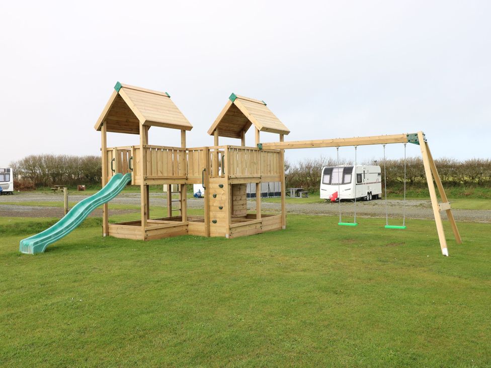 A playground structure with a slide and swings at Stone Crab Lodge in Haverfordwest