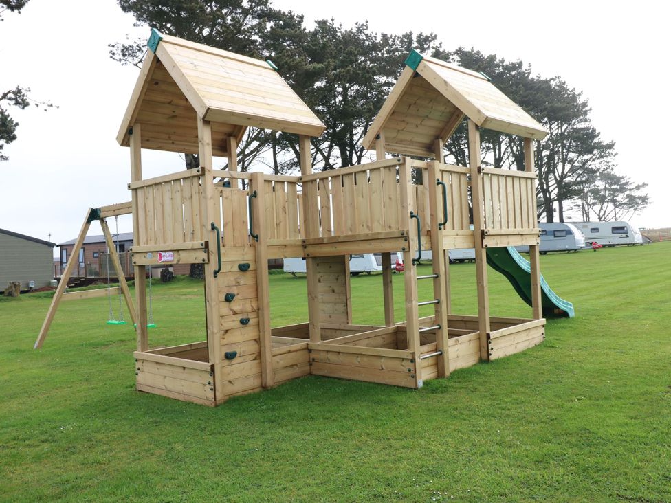 A play structure with a slide and climbing wall in an outdoor area at Stone Crab Lodge in Haverfordwest