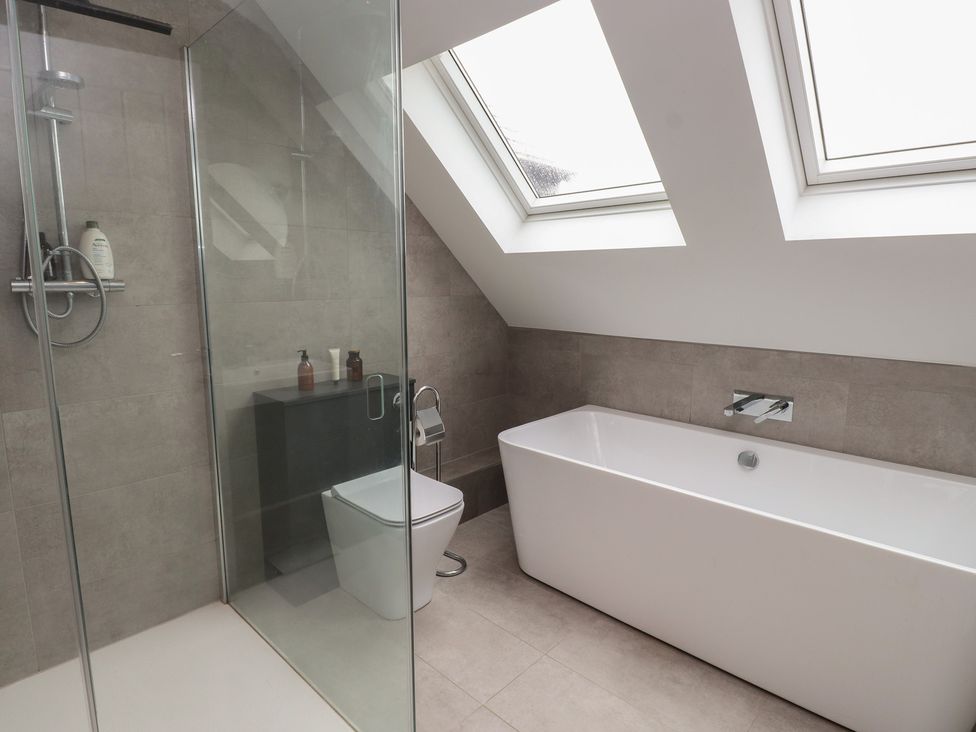 A bathroom with a shower, bathtub, toilet, and sink at Ty Hebog 