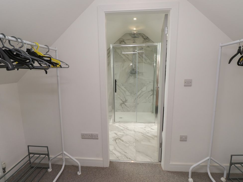 A bathroom with a shower and clothes hangers at Ty Hebog in 