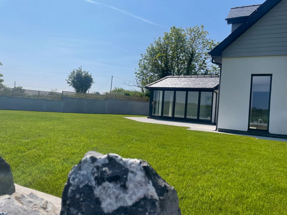 A garden with a house and grass at Ty Hebog Beaumaris