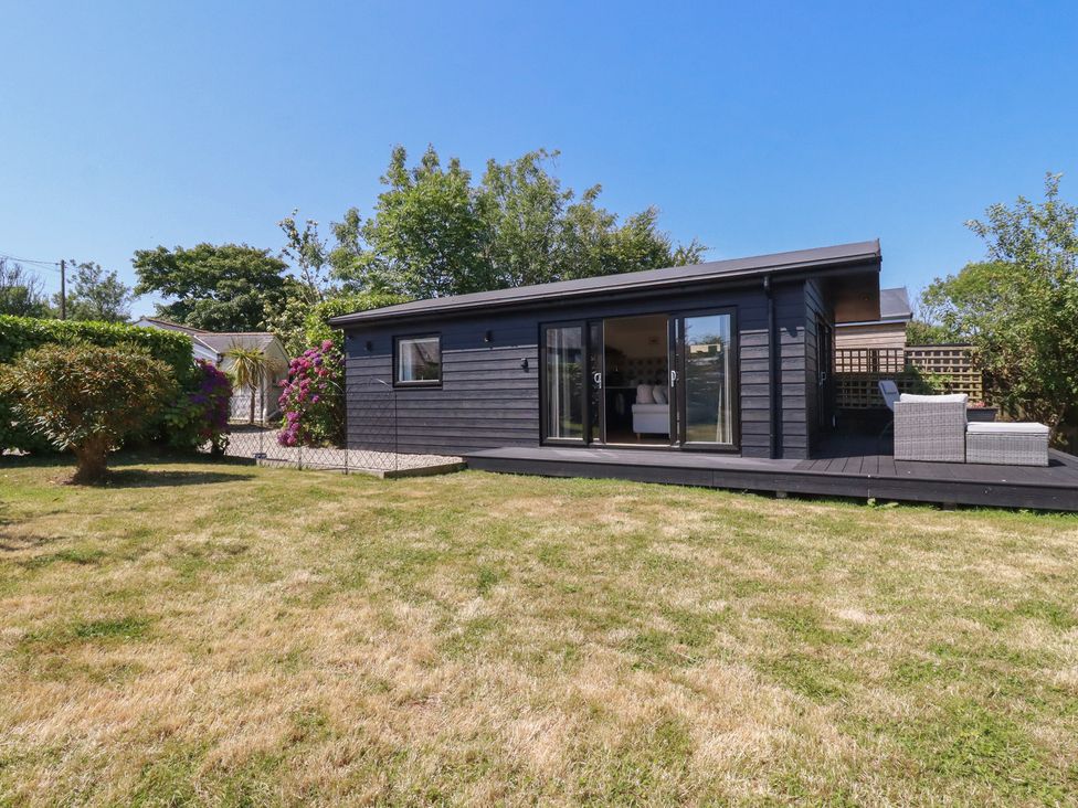 A garden with a wooden house and greenery at Wisteria Lodge in Redruth