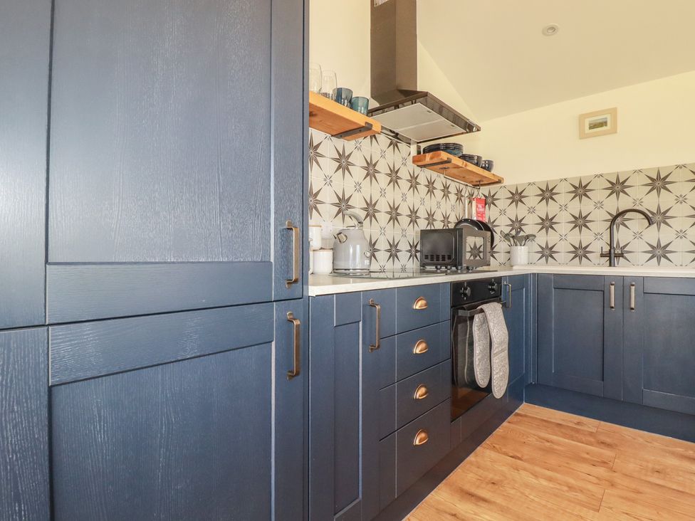 A kitchen with dark cabinets and a sink at Wisteria Lodge in Redruth