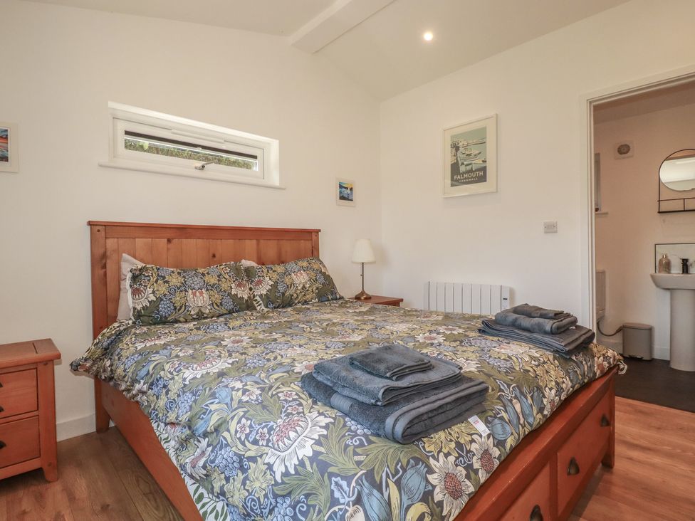 A bedroom with a bed and nightstand at Wisteria Lodge in Redruth
