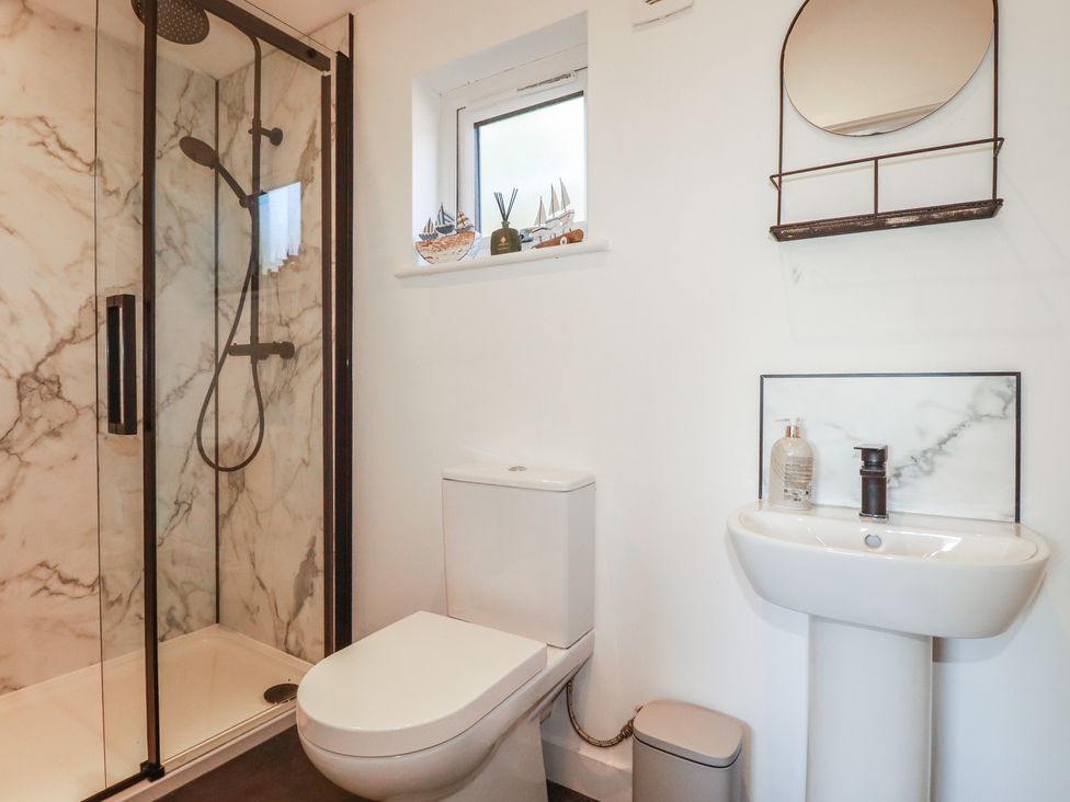 A bathroom featuring a shower, toilet, and sink at Wisteria Lodge in Redruth