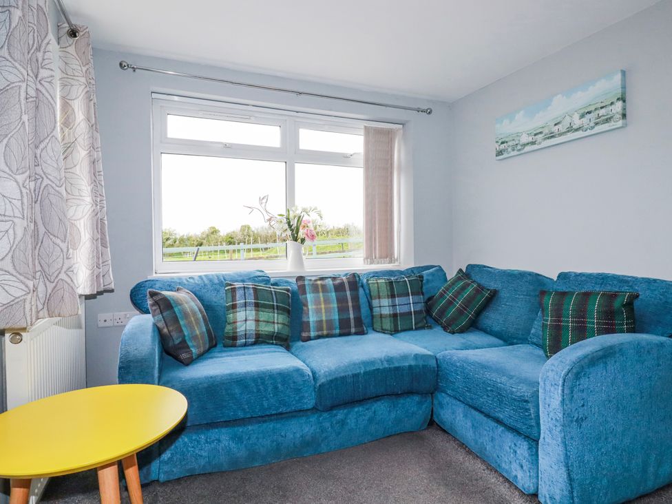 A living room with a blue sofa near a window at Likely Sunset in St. Austell