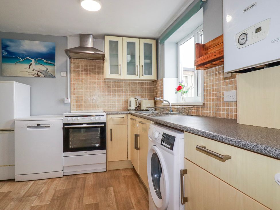 A kitchen with appliances including a fridge, oven, and washing machine at Likely Sunset in St. Austell