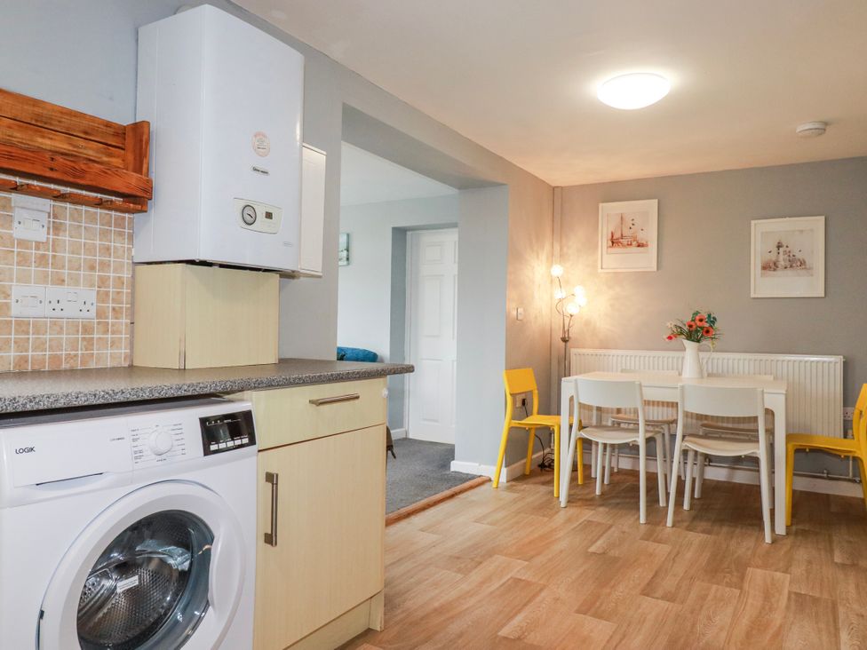 A kitchen with a washing machine and dining table at Likely Sunset in St. Austell