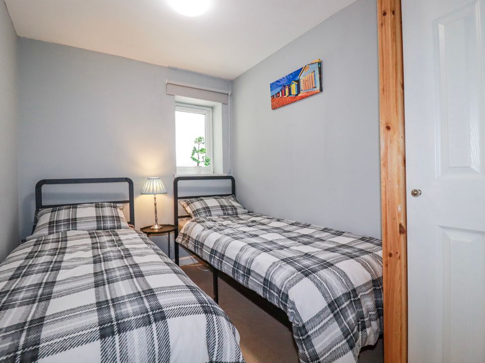 A bedroom with two single beds and a lamp at Likely Sunset in St. Austell