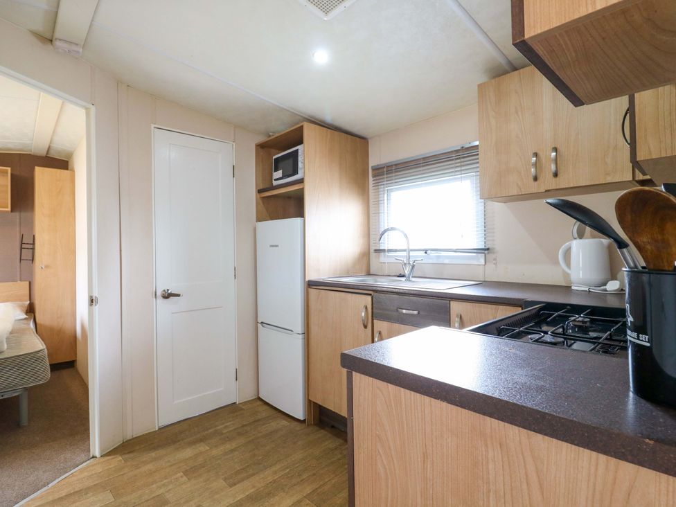 A kitchen with refrigerator and stove at Caravan 102 seawick in Clacton-on-Sea