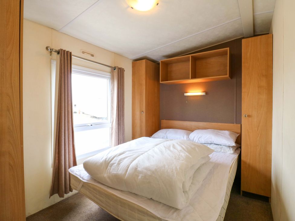 A bedroom with a bed and wardrobe at Caravan 102 seawick Clacton-on-Sea