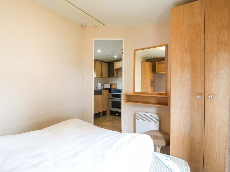 A bedroom with a bed and wardrobe at Caravan 102 seawick in Clacton-on-Sea
