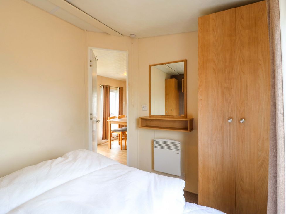 A bedroom with a bed, wardrobe, and a mirror at Caravan 102 seawick Clacton-on-Sea