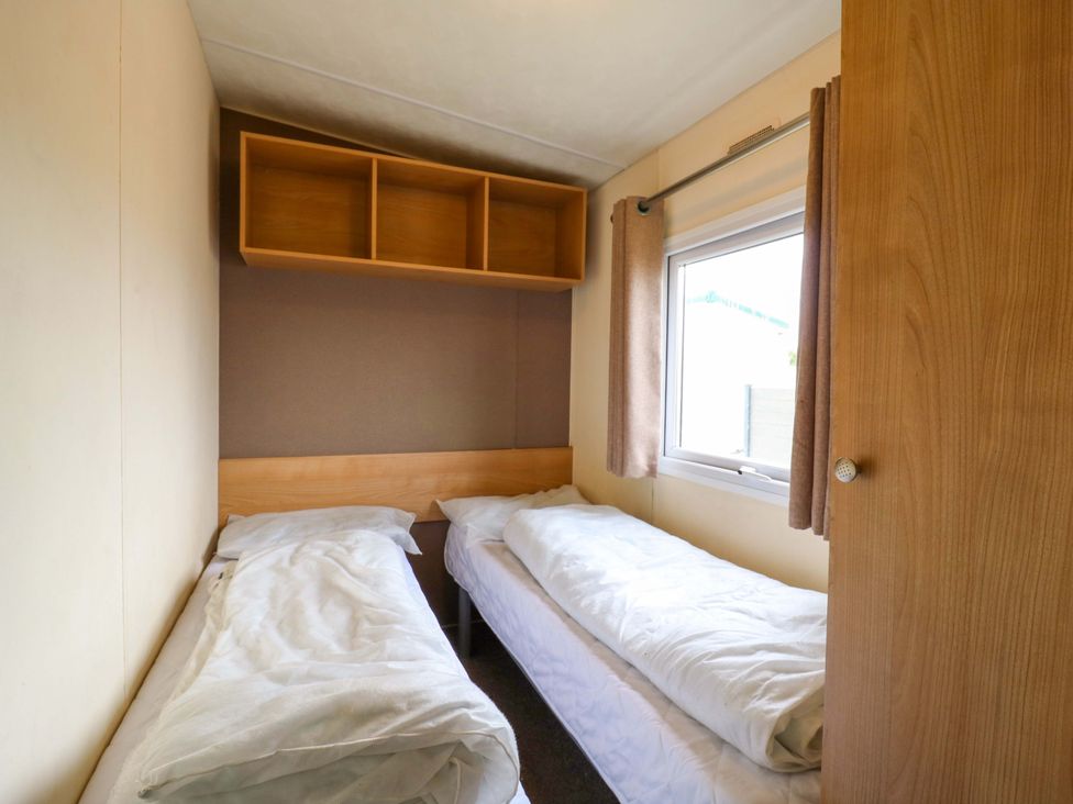 A bedroom with two beds and a window at Caravan 102 seawick Clacton-on-Sea