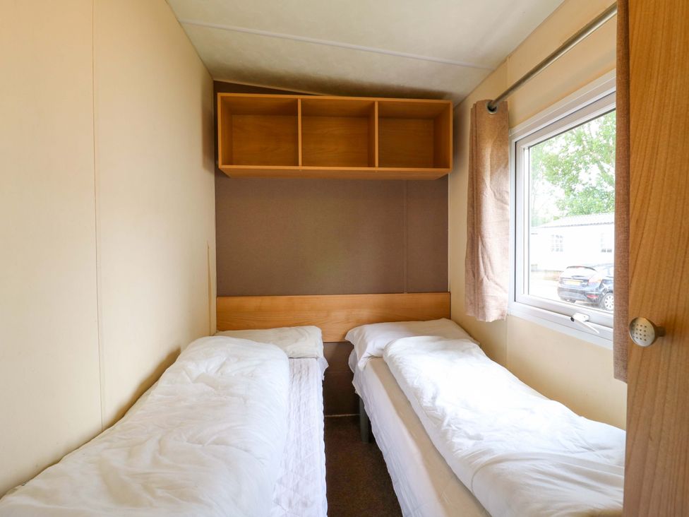 A bedroom with two single beds and a shelf at Caravan 102 seawick in Clacton-on-Sea
