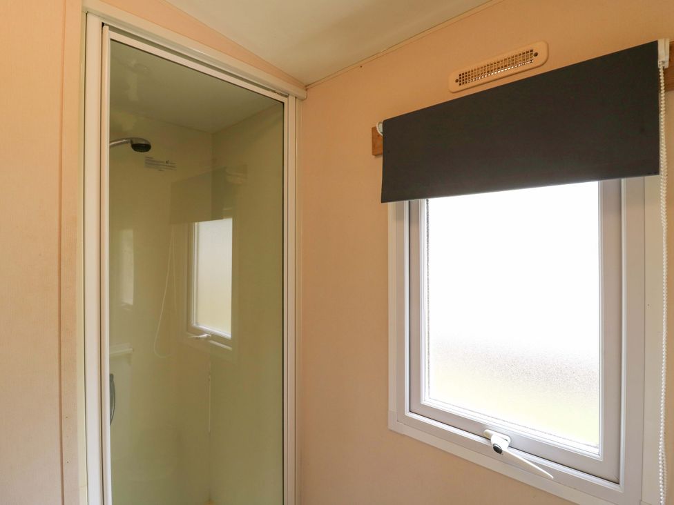 A bathroom with shower and window at Caravan 102 seawick Clacton-on-Sea