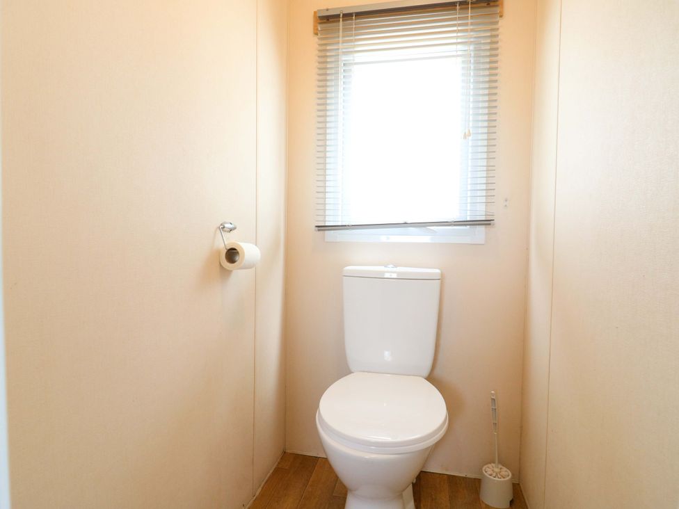 A toilet with a window in a bathroom at Caravan 102 seawick Clacton-on-Sea