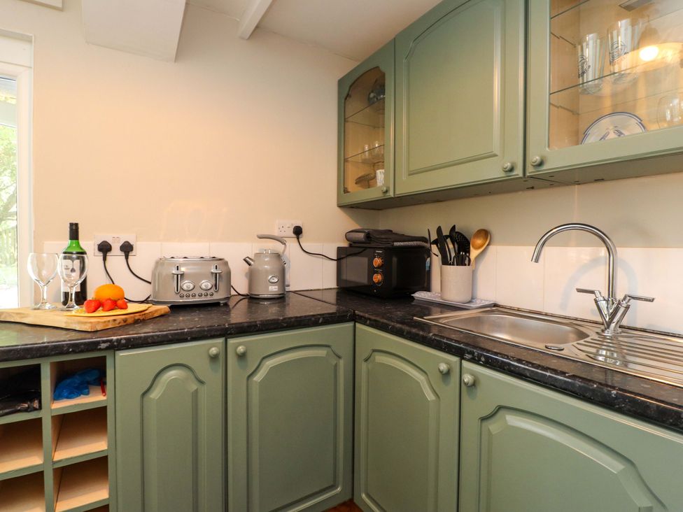 A kitchen with cabinets and appliances at Woodman's Lodge in Llanallgo near Moelfre