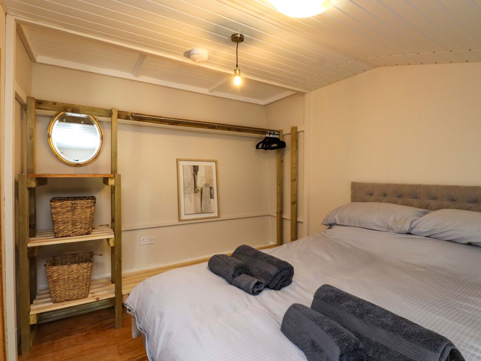 A bedroom with a bed and shelving at Woodman's Lodge Llanallgo near Moelfre