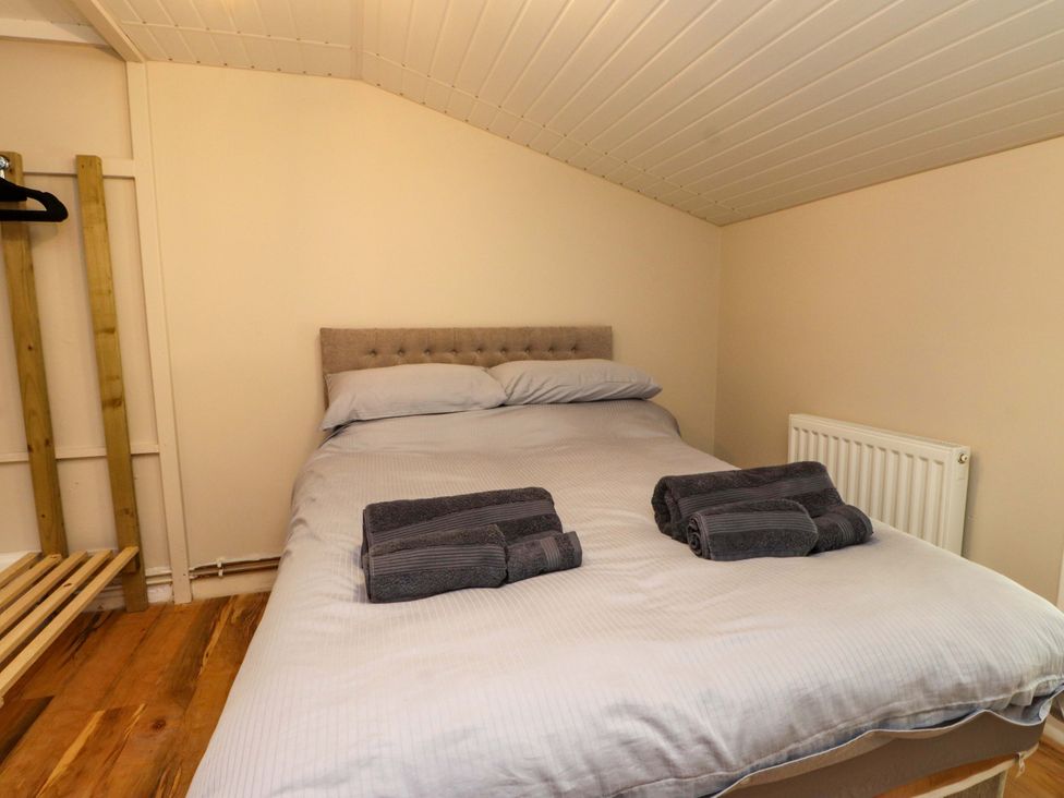 A bedroom with a bed and towels at Woodman's Lodge Llanallgo near Moelfre