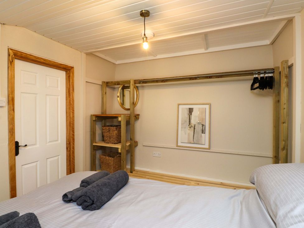 A bedroom with a bed and a shelf at Woodman's Lodge Llanallgo near Moelfre