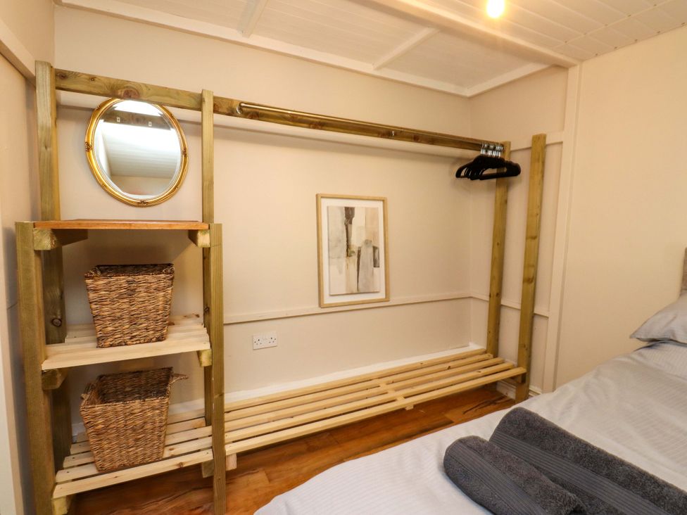 A bedroom with a clothing rail and storage baskets at Woodman's Lodge in Llanallgo near Moelfre
