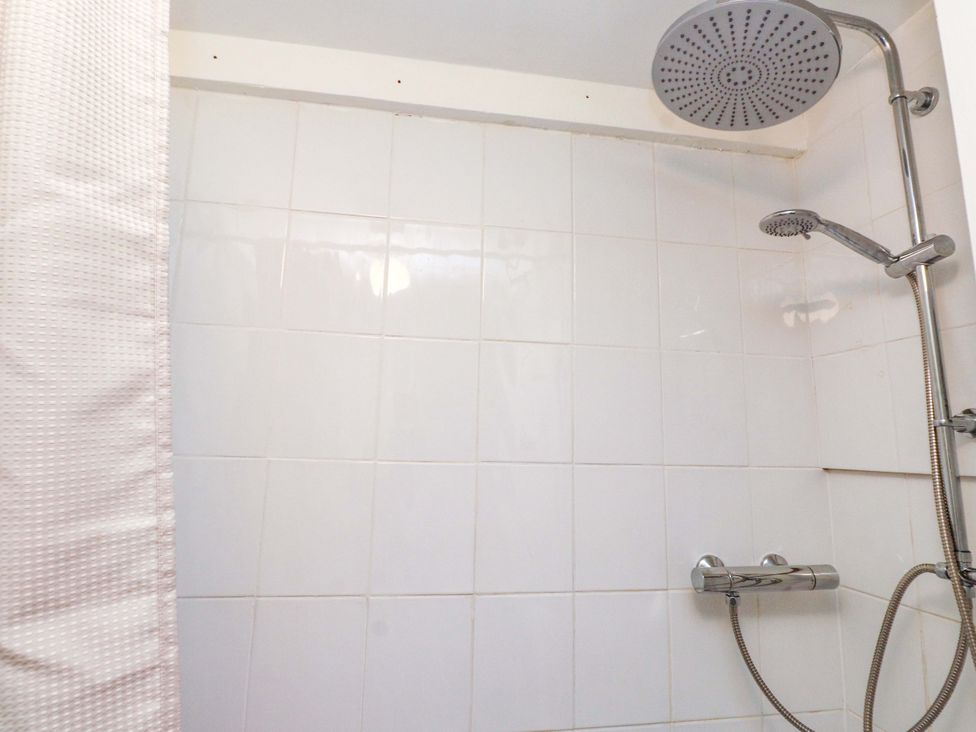 A shower area with tiles and a showerhead at Woodman's Lodge in Llanallgo near Moelfre
