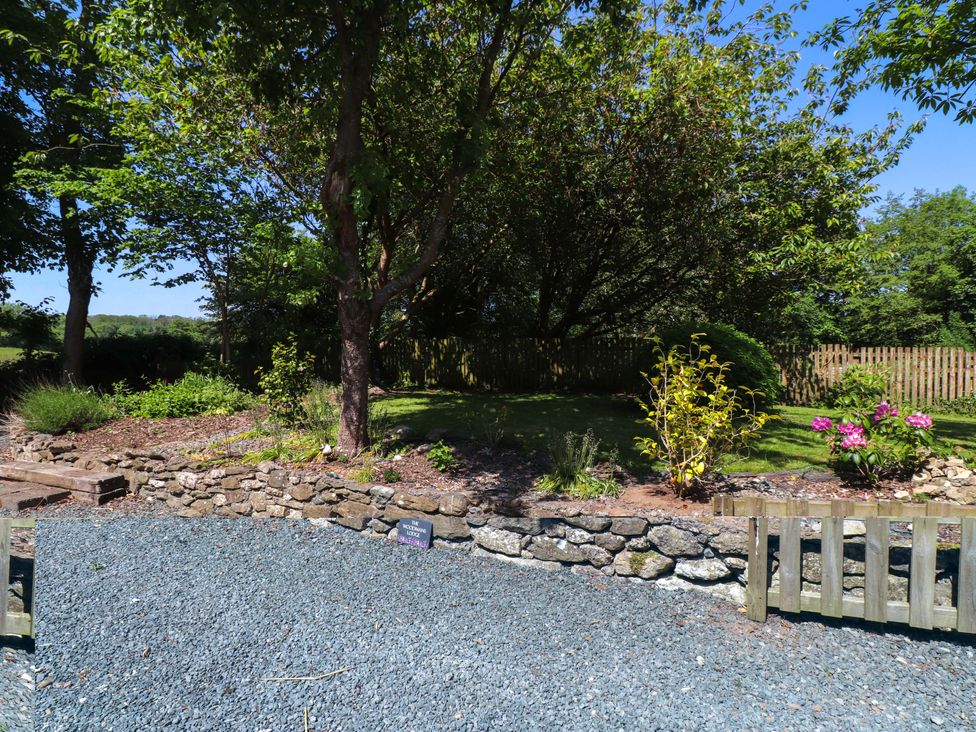 A garden with trees and flowering plants at Woodman's Lodge in Llanallgo near Moelfre