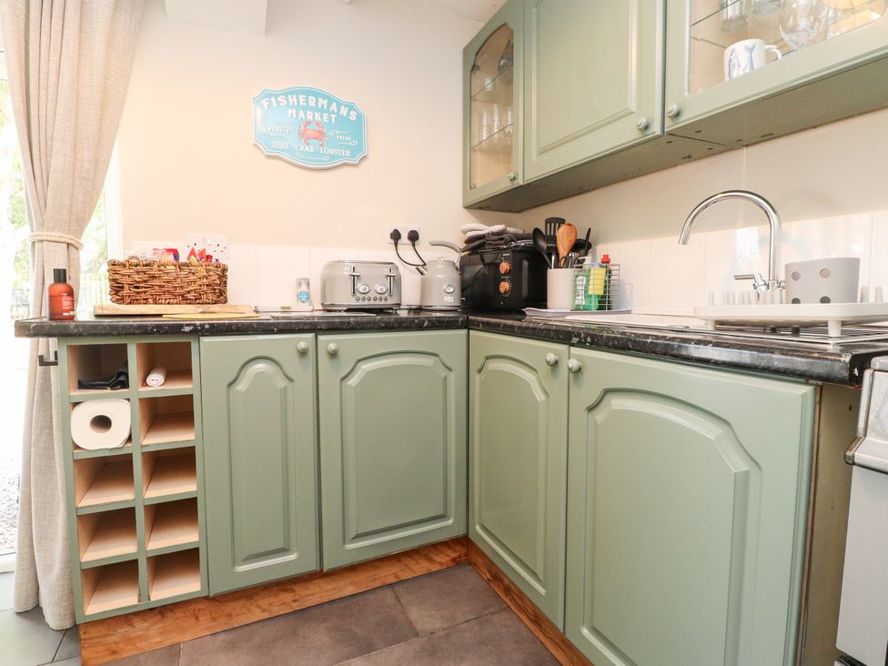 A kitchen with cabinets and a sink at Woodman's Lodge in Llanallgo near Moelfre