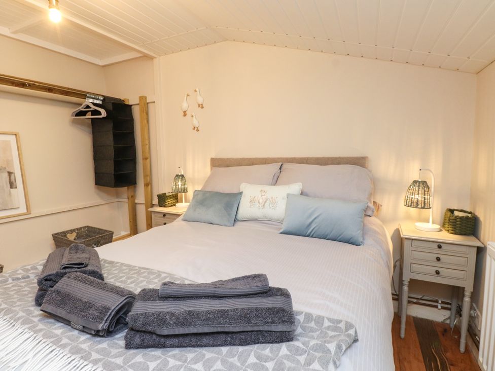 A bedroom with a bed and towels on a decorative blanket at Woodman's Lodge in Llanallgo near Moelfre