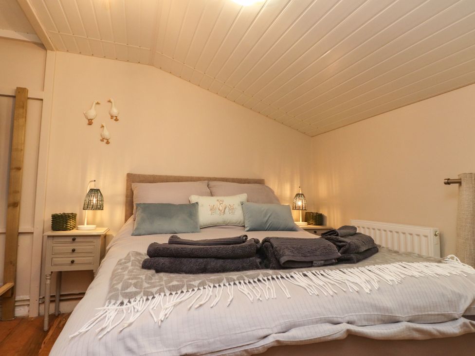 A bedroom with a bed and bedside table at Woodman's Lodge in Llanallgo near Moelfre